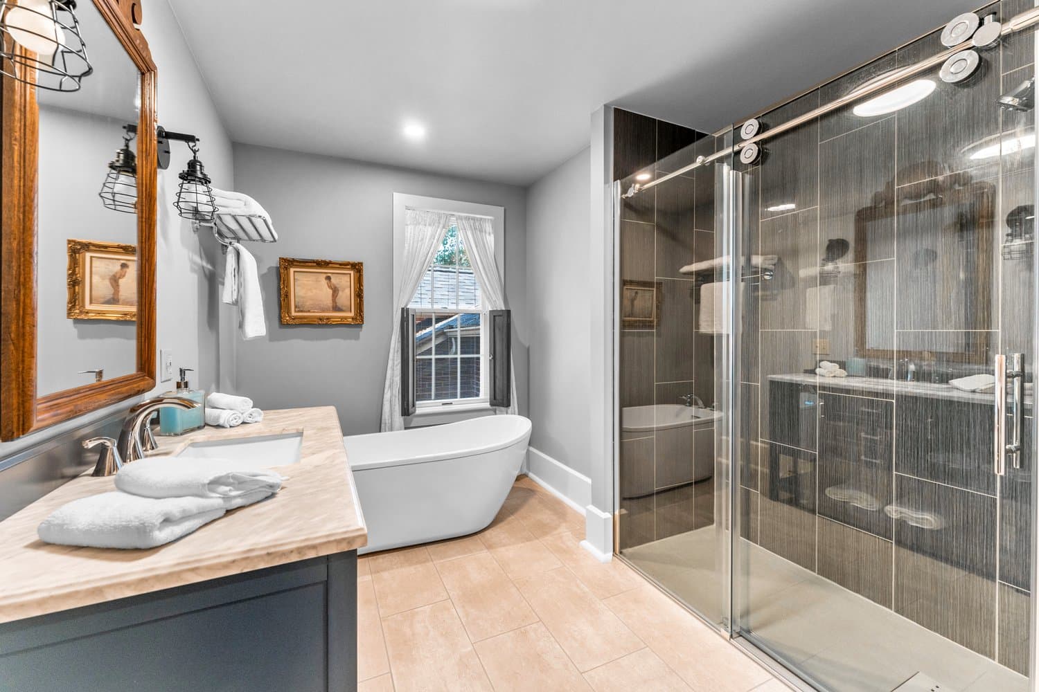Pristine modern bathroom with oversized glass-enclosed tiled shower, sink with vanity, and soaking tub.