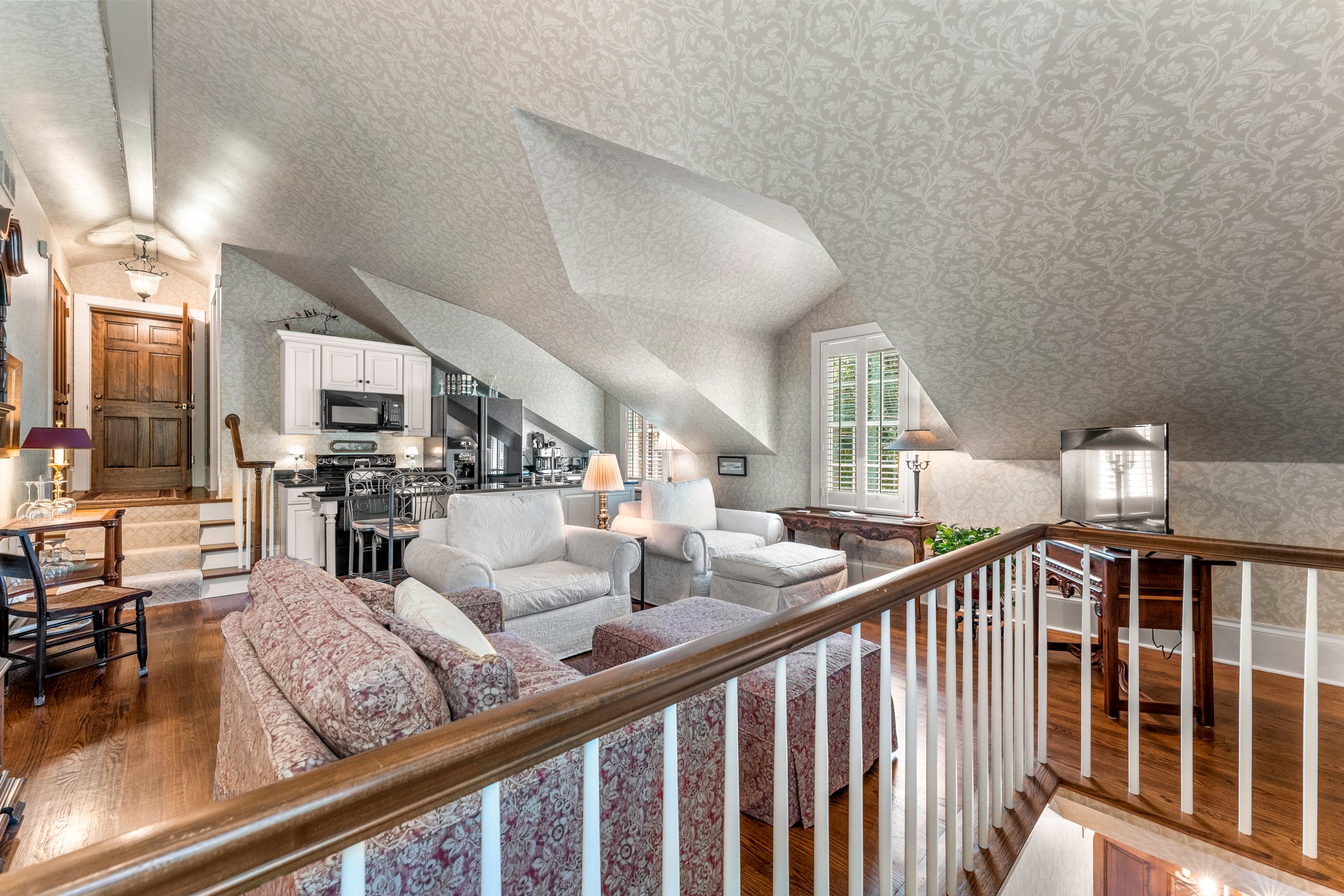 Light and airy living area with plush comfortable furniture including a pull out sofa and kitchen visible in background.