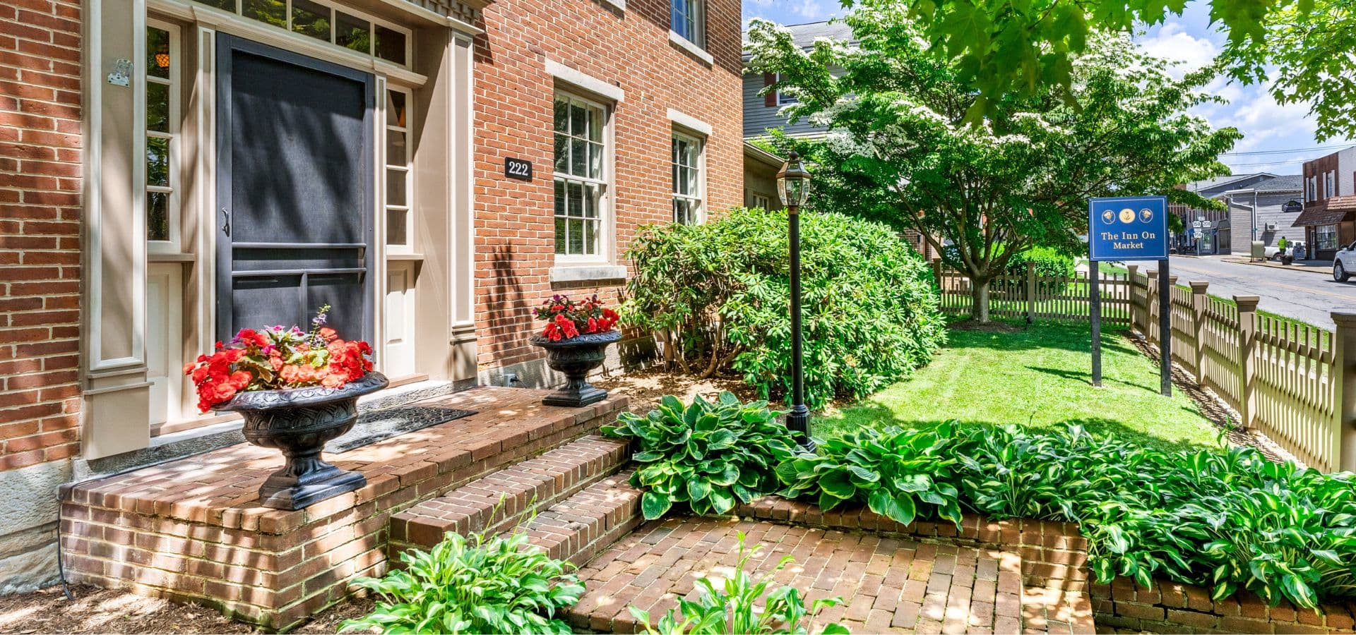 A welcoming entrance featuring brick steps, potted flowers, and a sign for "The Inn On Market."