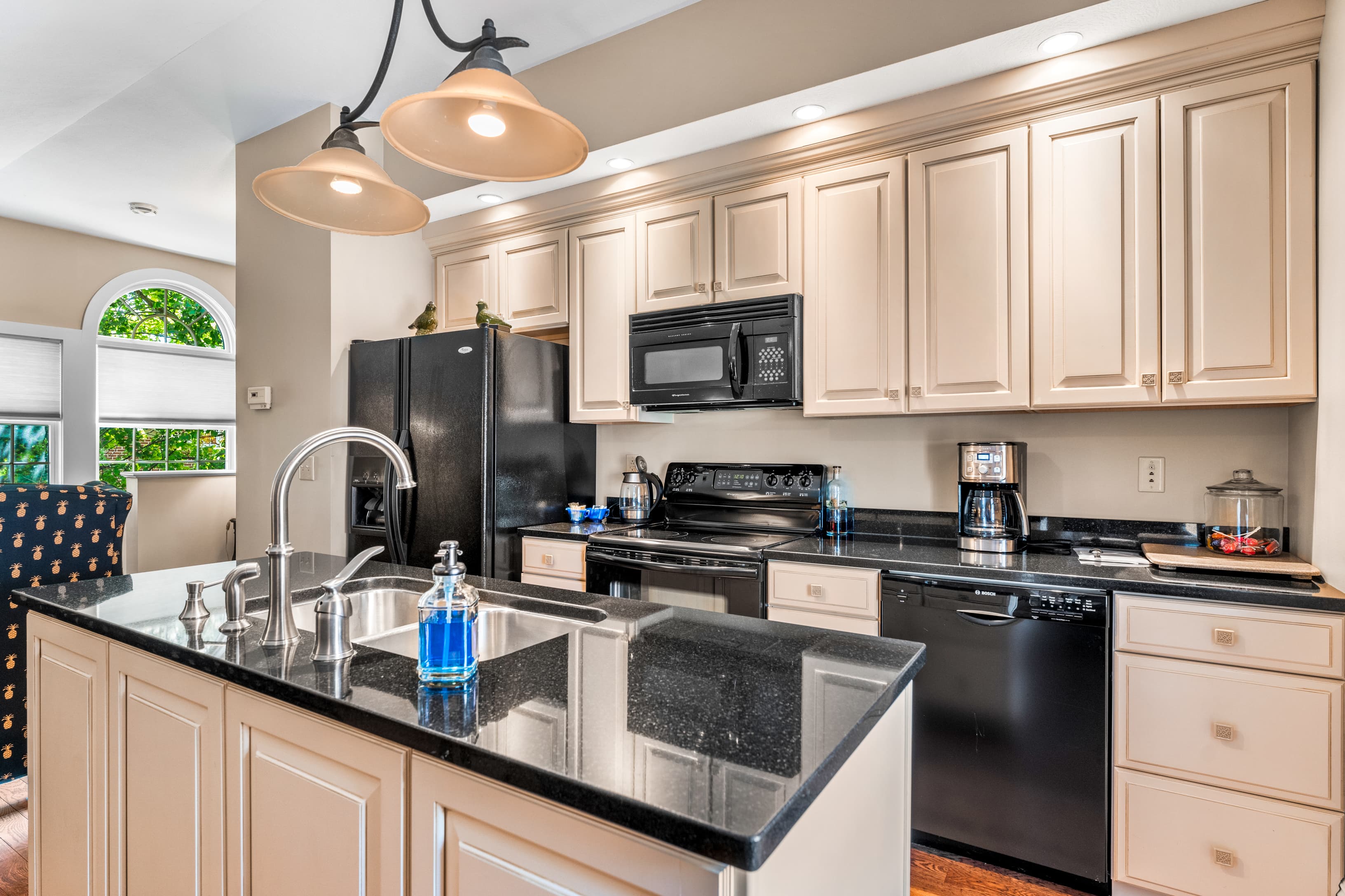 A modern kitchen featuring black appliances, granite countertops, and light-colored cabinetry.